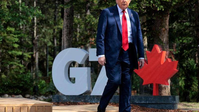 Donald Trump îmbrăcat cu un costum bleumarin și o cravată roșie, mergând