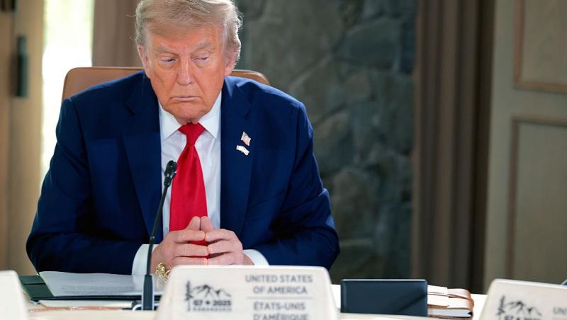 Donald Trump îmbrăcat cu un costum bleumarin și o cravată roșie, vorbind la microfon