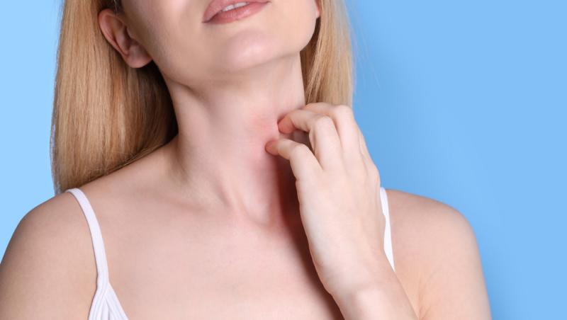 o femeie pe fundal albastru care se scarpină pe gât