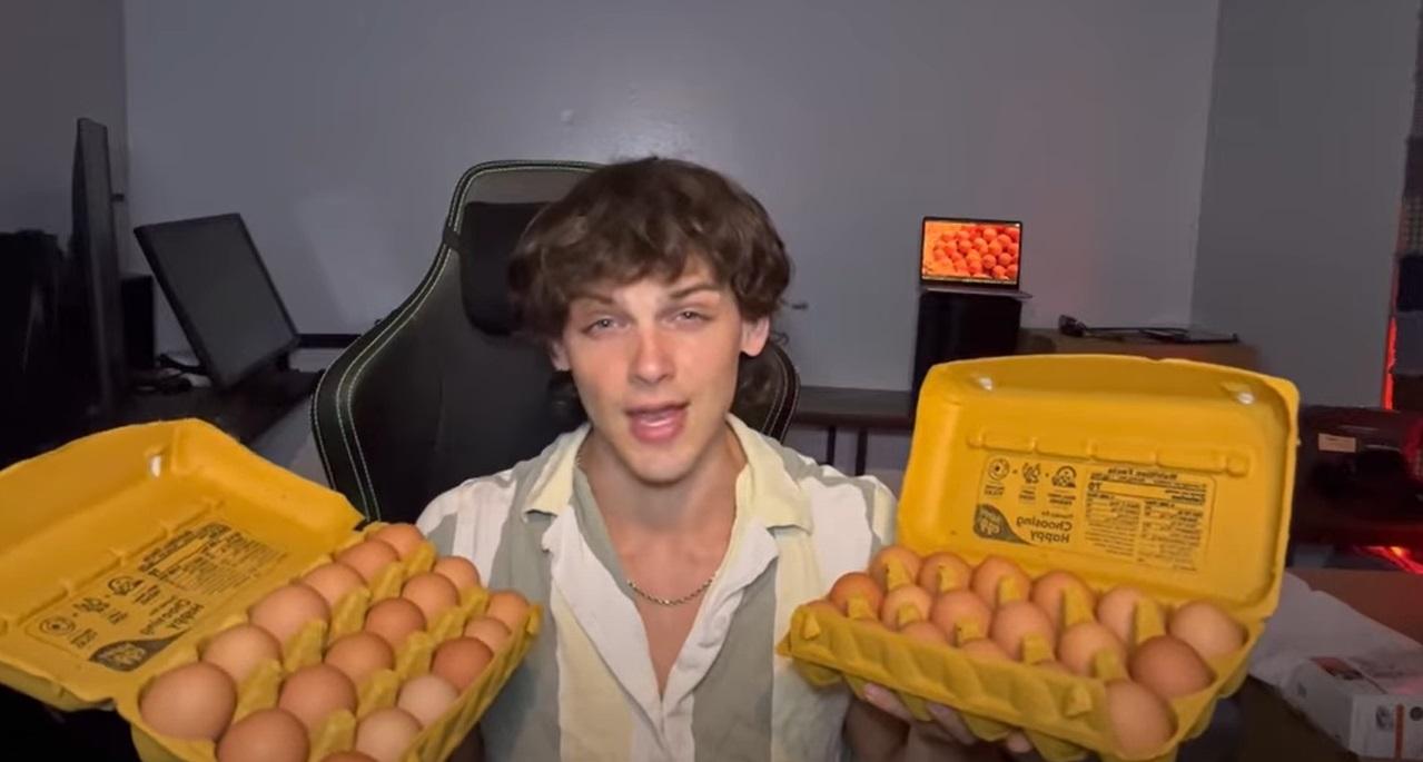 Un tânăr care stă pe scaun cu două cofrage de ouă în mâini