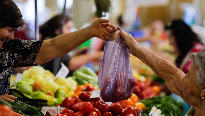 O femeie care cumpără legume de la o tarabă în piața Obor din București, România