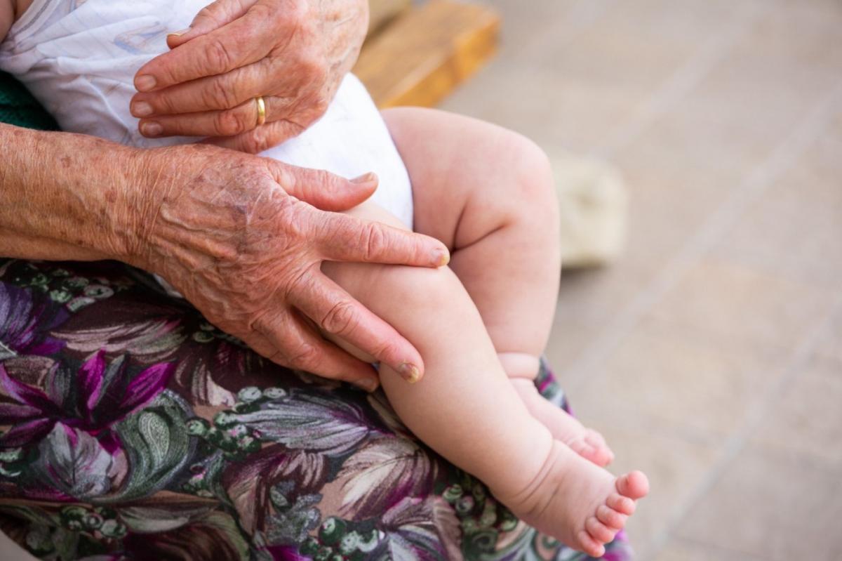 imagine cu o batrana care tine un copil in brate