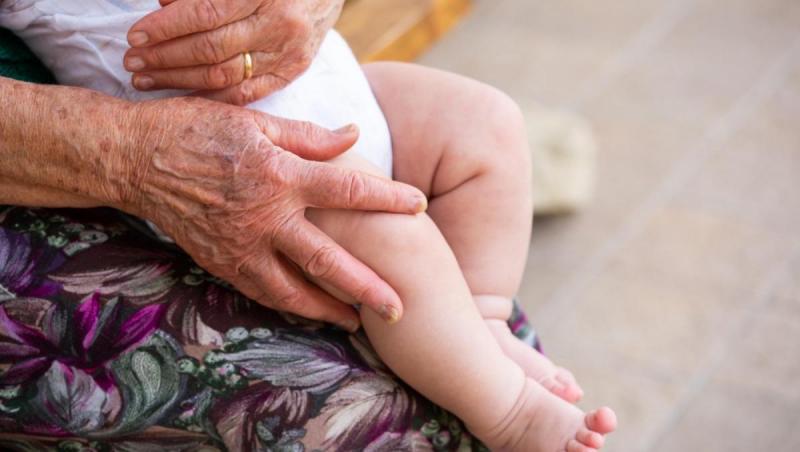 imagine cu o batrana care tine un copil in brate