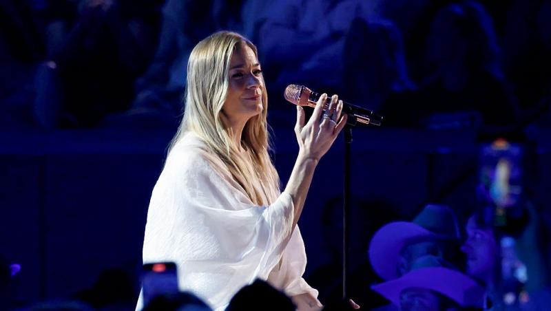 LeAnn Rimes îmbrăcată într-o ținută albă, cântând pe scenă