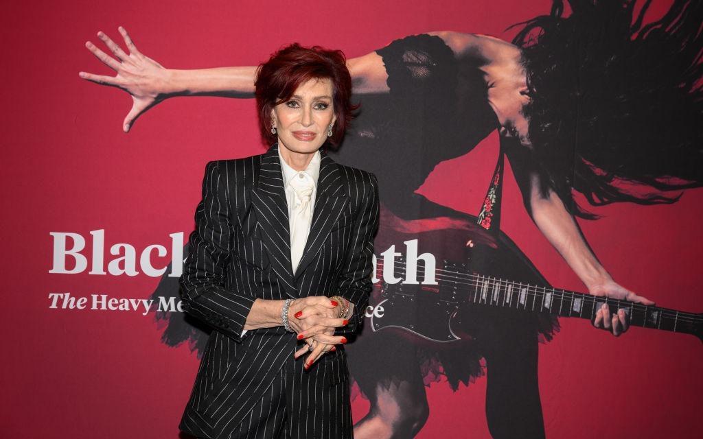Sharon Osbourne îmbrăcată cu un costum negru cu dungi albe
