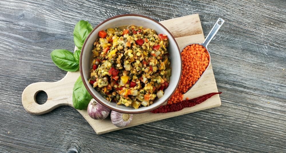 Salată caldă de linte cu legume și verdeață într-un castron