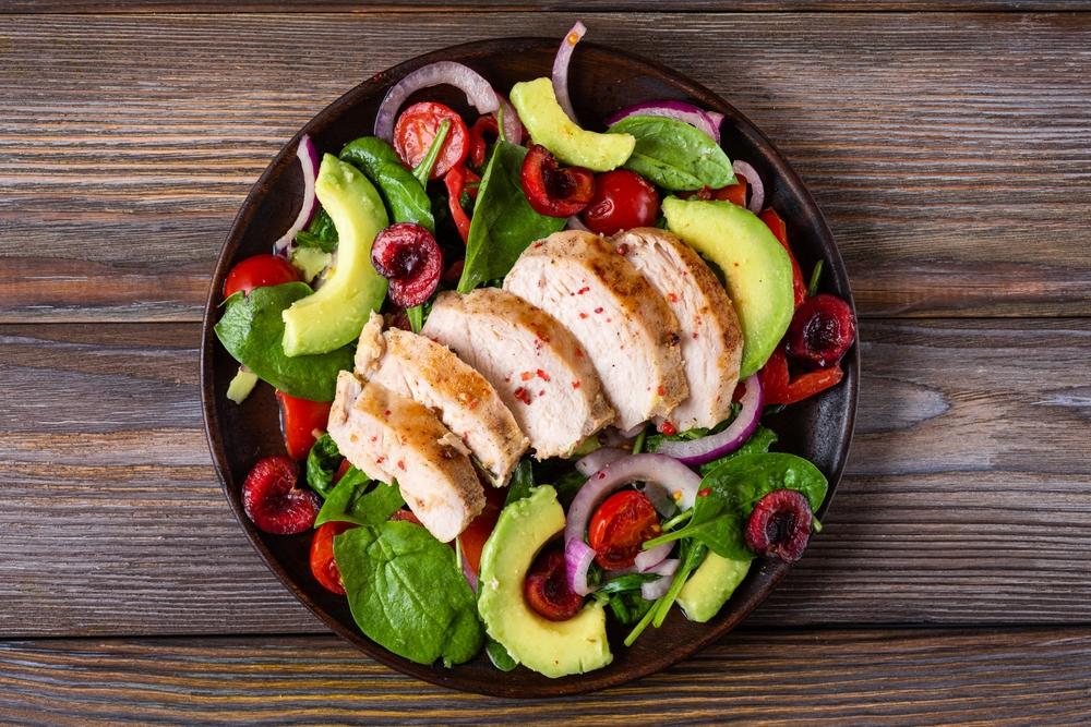 Salată cu piept de pui, avocado și spanac baby într-un bol maro