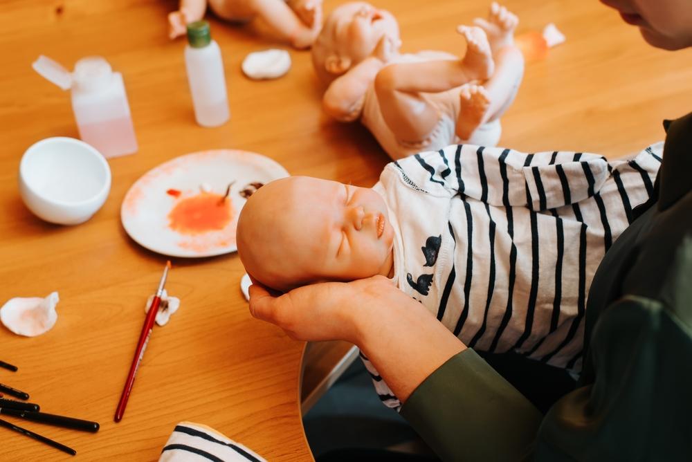 femeie care ține o păpușă reborn în mână după ce a confecționat-o