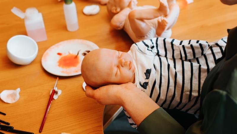 femeie care ține o păpușă reborn în mână după ce a confecționat-o
