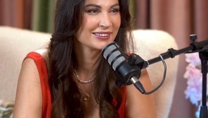 Nicoleta Luciu îmbrăcată într-o rochie roșie vorbind la microfon în timpul unui podcast