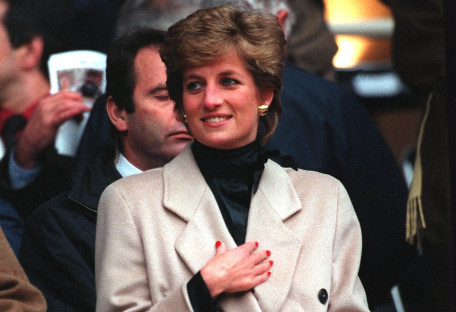 Prințesa Diana îmbrăcată cu un palton bej, accesorizat cu o eșarfă neagră