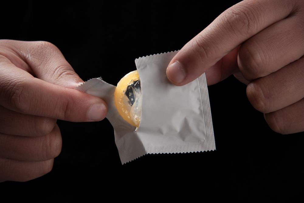 bărbat care desface un prezervativ