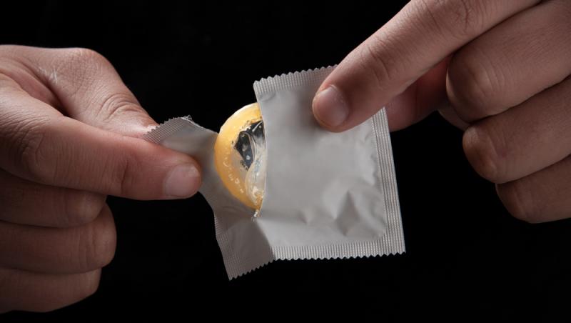 bărbat care desface un prezervativ