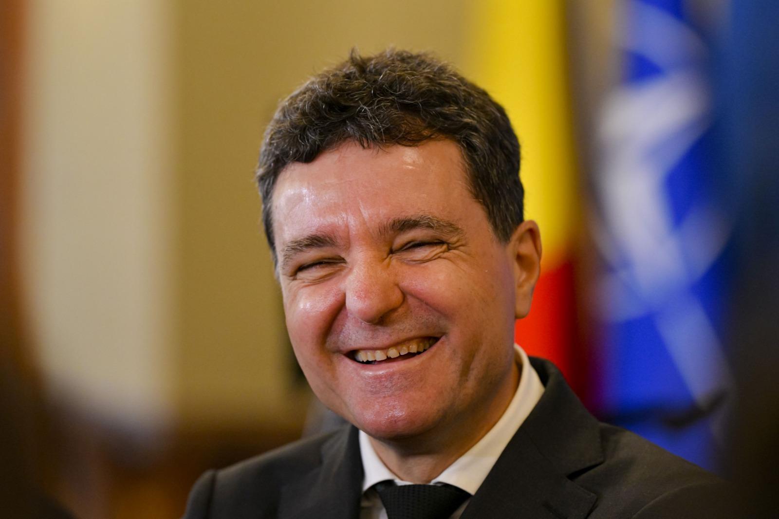 Nicușor Dan îmbrăcat cu un costum negru, râzând