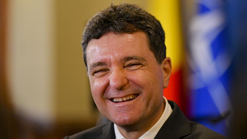Nicușor Dan îmbrăcat cu un costum negru, râzând
