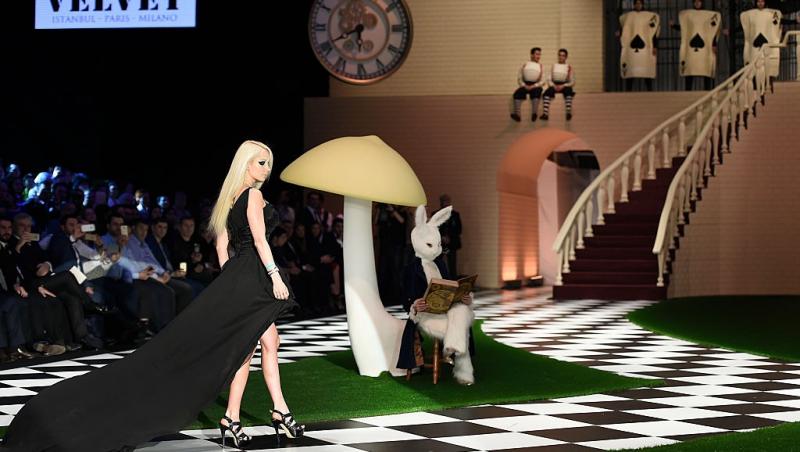 Valeria Lukyanova îmbrăcată într-o rochie neagră cu trenă lungă, defilând la un eveniment