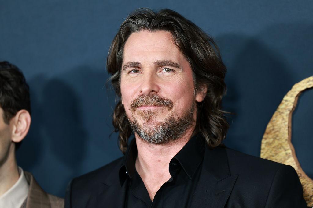 Christian Bale îmbrăcat cu o cămașă neagră sub un sacou negru