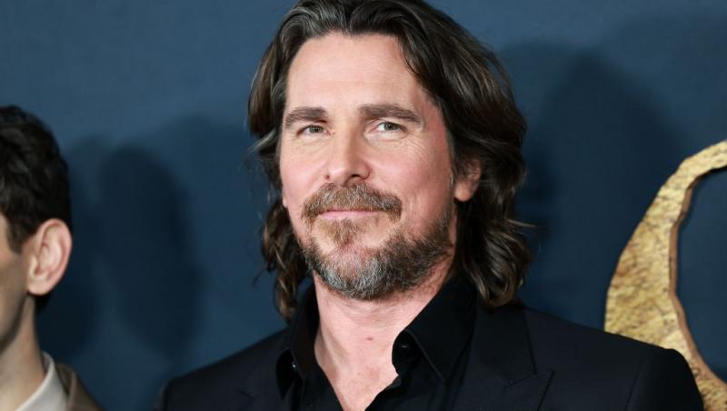 Christian Bale îmbrăcat cu o cămașă neagră sub un sacou negru