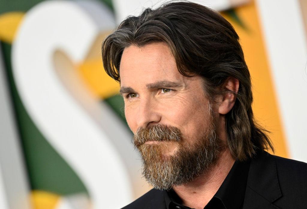 Christian Bale îmbrăcat cu o cămașă neagră sub un sacou negru