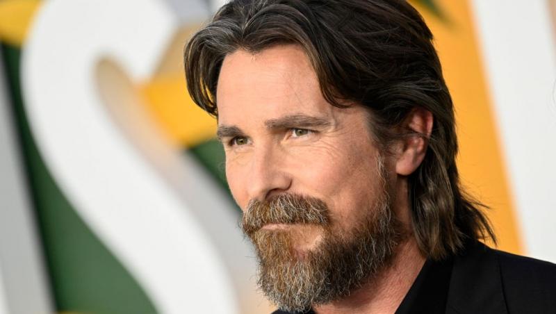 Christian Bale îmbrăcat cu o cămașă neagră sub un sacou negru