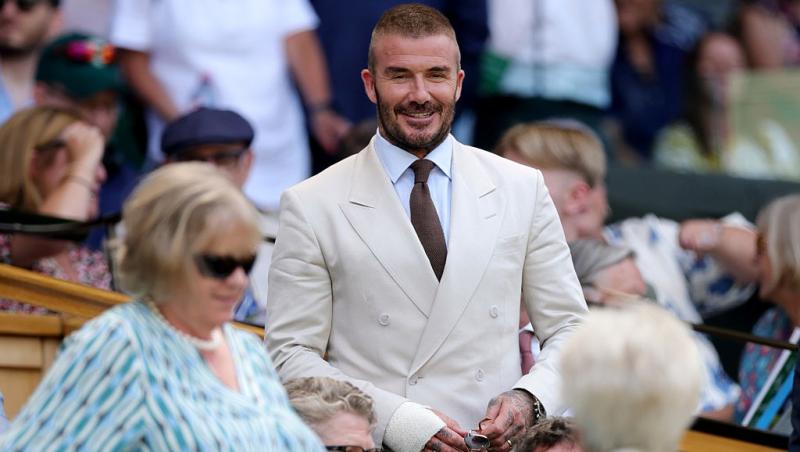 David Beckham alături mama lui, Sandra, la un meci de tenis, ambii îmbrăcați în ținute elegante bej
