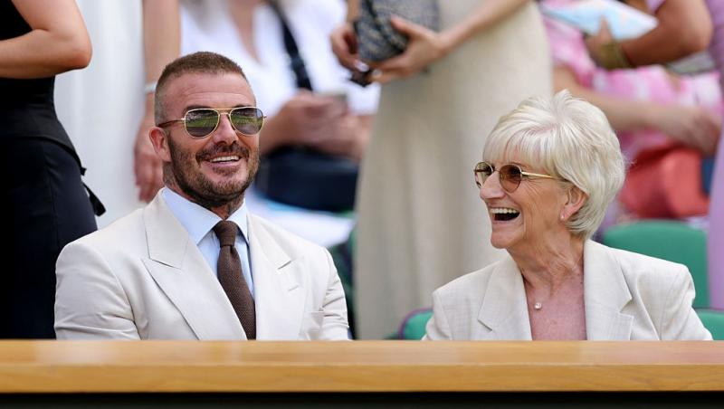 David Beckham alături mama lui, Sandra, la un meci de tenis, ambii îmbrăcați în ținute elegante bej