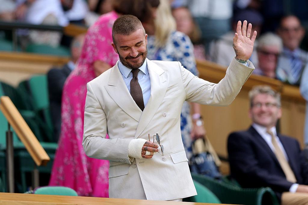 David Beckham la un meci de tenis, îmbrăcat într-un costum bej
