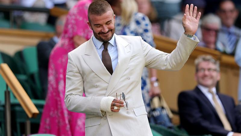 David Beckham la un meci de tenis, îmbrăcat într-un costum bej