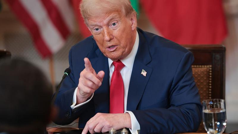 Donald Trump îmbrăcat cu un costum bleumarin și o cravată roșie, vorbind