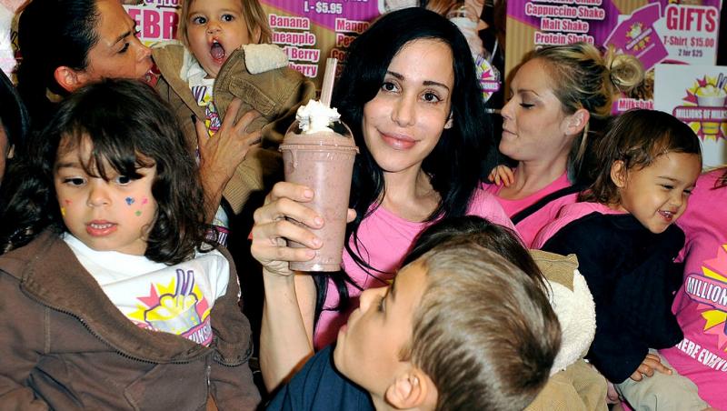 Nadya Suleman îmbrăcată cu un tricou roz și pantaloni din denim, înconjurată de copii