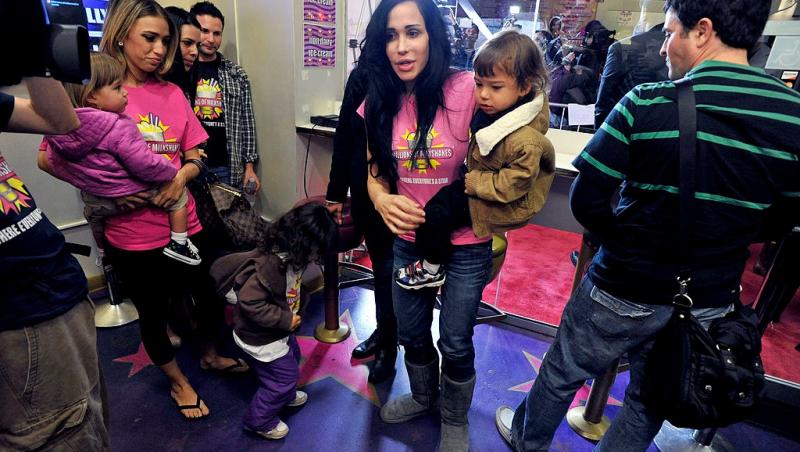 Nadya Suleman îmbrăcată cu un tricou roz și pantaloni din denim, înconjurată de copii