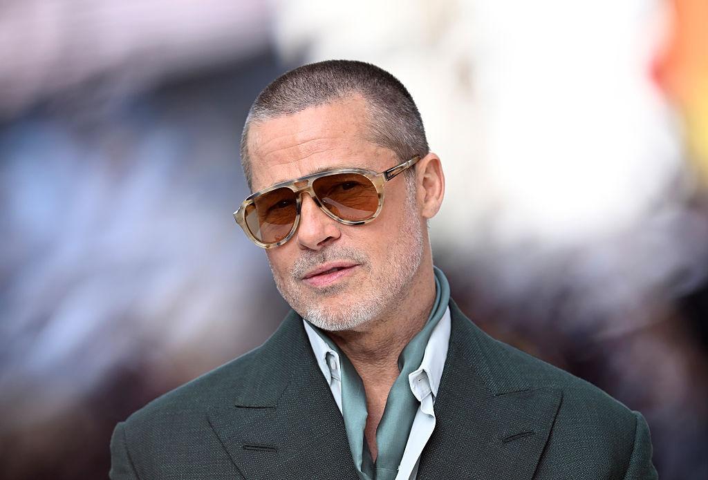 Brad Pitt îmbrăcat cu un sacou gri și ochelari de soare