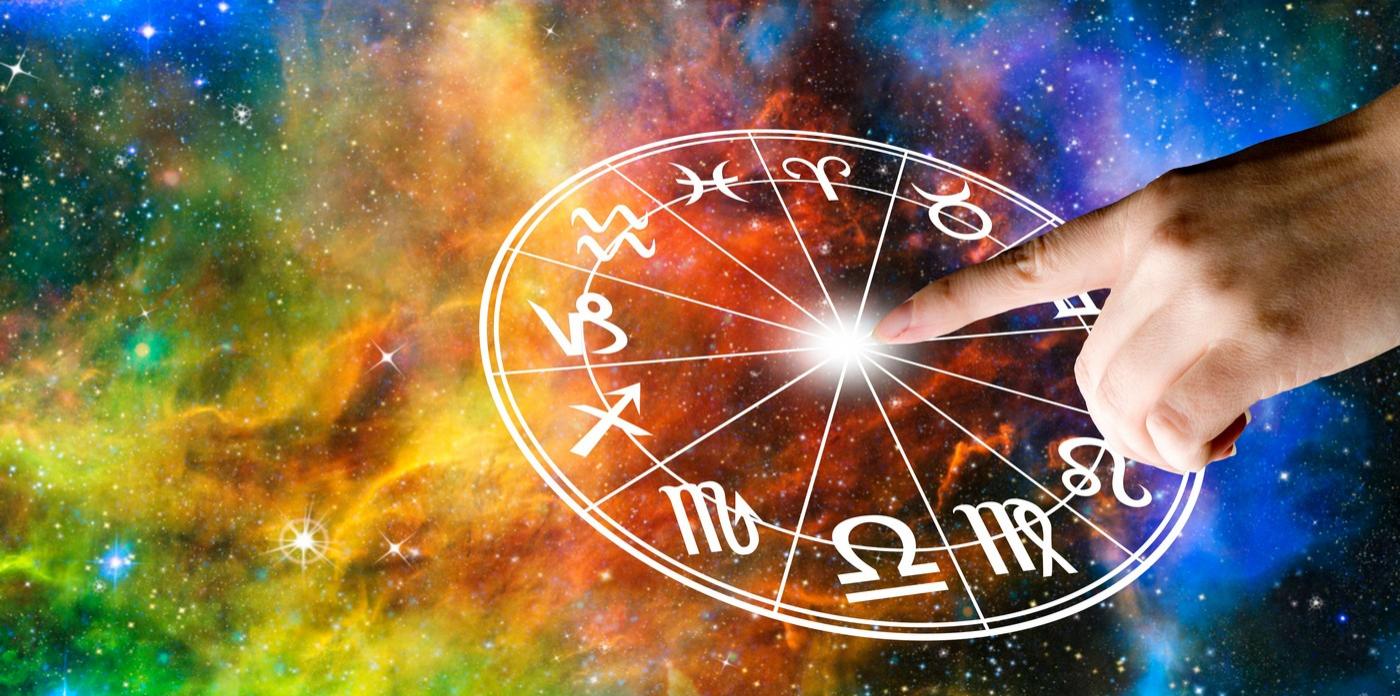 imagine cu cercul cu zodii si fundal multicilor ca de galaxie si mana unei persoane