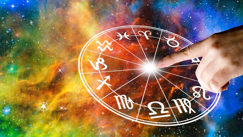 imagine cu cercul cu zodii si fundal multicilor ca de galaxie si mana unei persoane