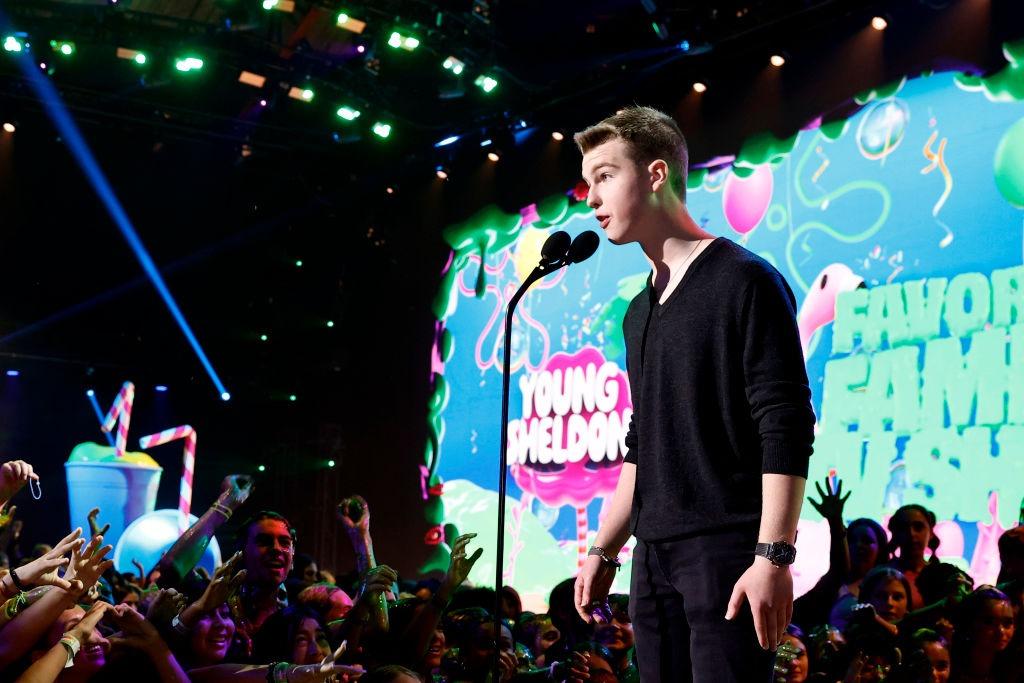 Iain Armitage îmbrăcat într-o ținută neagră, vorbind la microfon