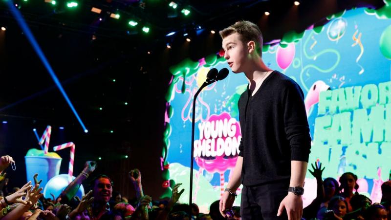 Iain Armitage îmbrăcat într-o ținută neagră, vorbind la microfon