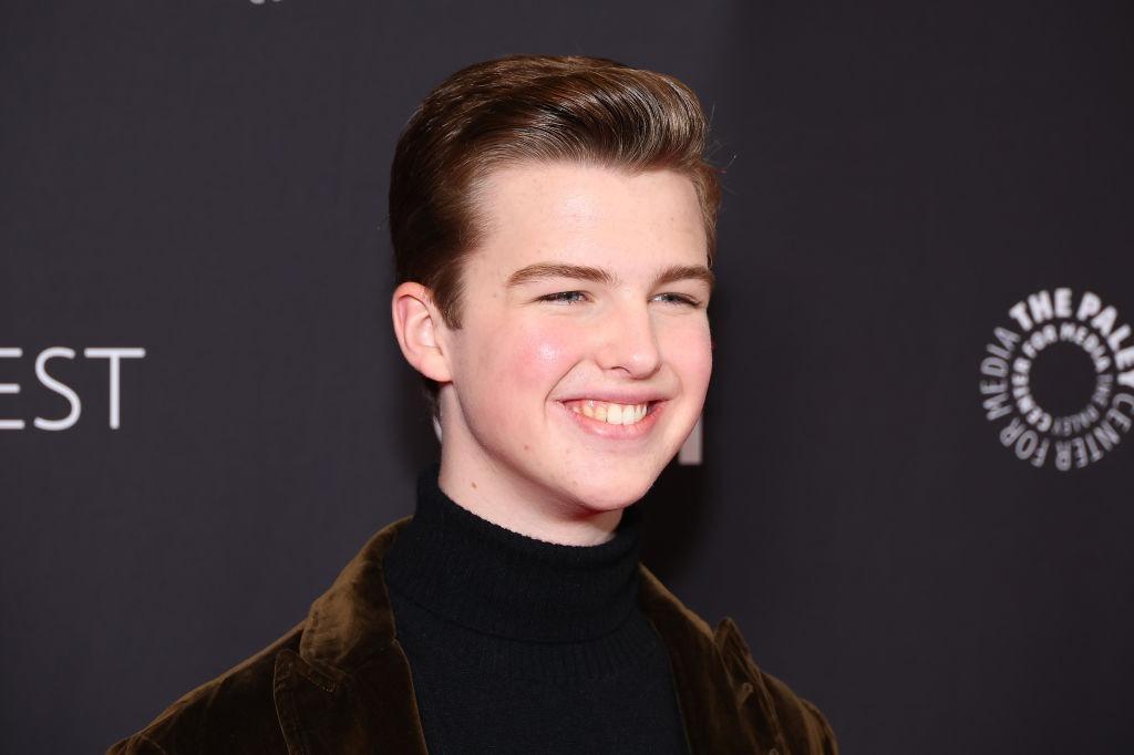 Iain Armitage îmbrăcat cu un pulover negru, sub un sacou maro