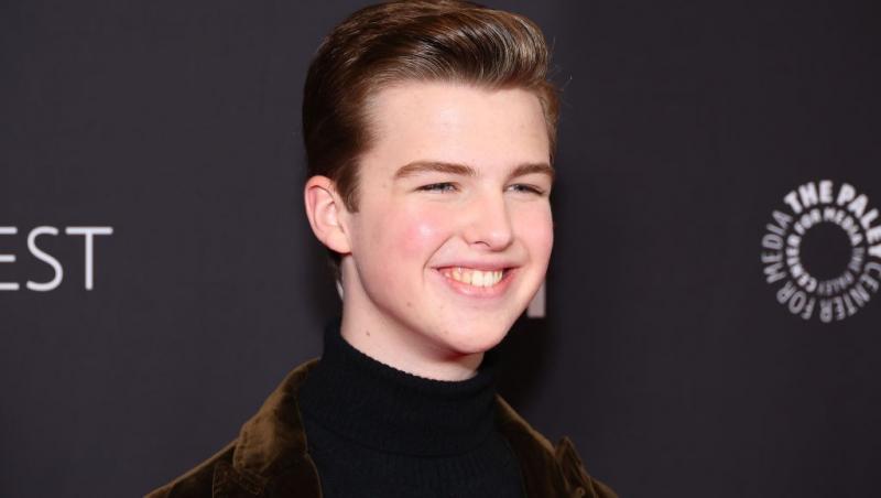 Iain Armitage îmbrăcat cu un pulover negru, sub un sacou maro