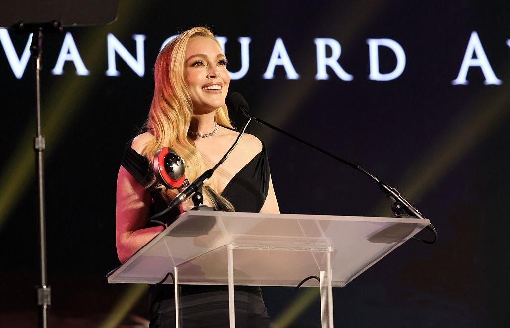 Lindsay Lohan îmbrăcată într-o rochie neagră, vorbind la microfon