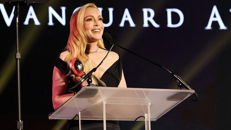 Lindsay Lohan îmbrăcată într-o rochie neagră, vorbind la microfon