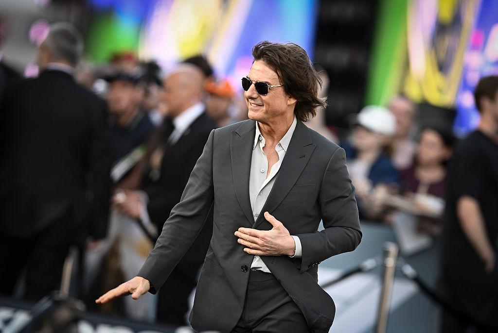 Tom Cruise îmbrăcat cu un costum gri, accesorizat cu ochelari de soare