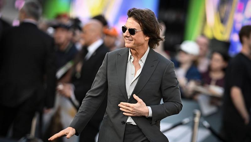 Tom Cruise îmbrăcat cu un costum gri, accesorizat cu ochelari de soare
