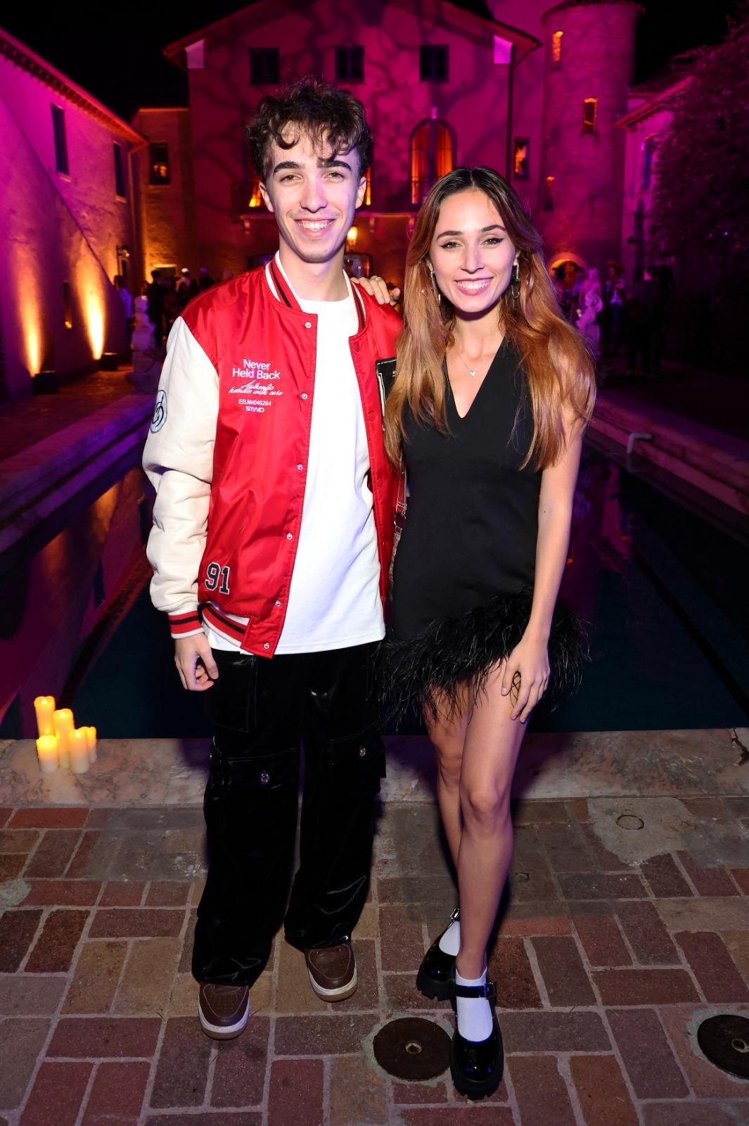 Răzvan Gogan îmbrăcat cu pantaloni negri și o jachetă roșie cu mâneci albe, alături de Andra Gogan, îmbrăcată într-o rochie neagră