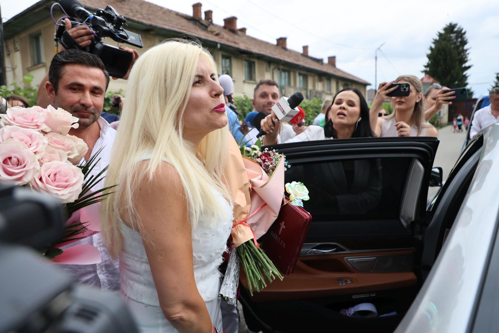 Elena Udrea îmbrăcată într-o ținută complet albă, înconjurată de reporteri