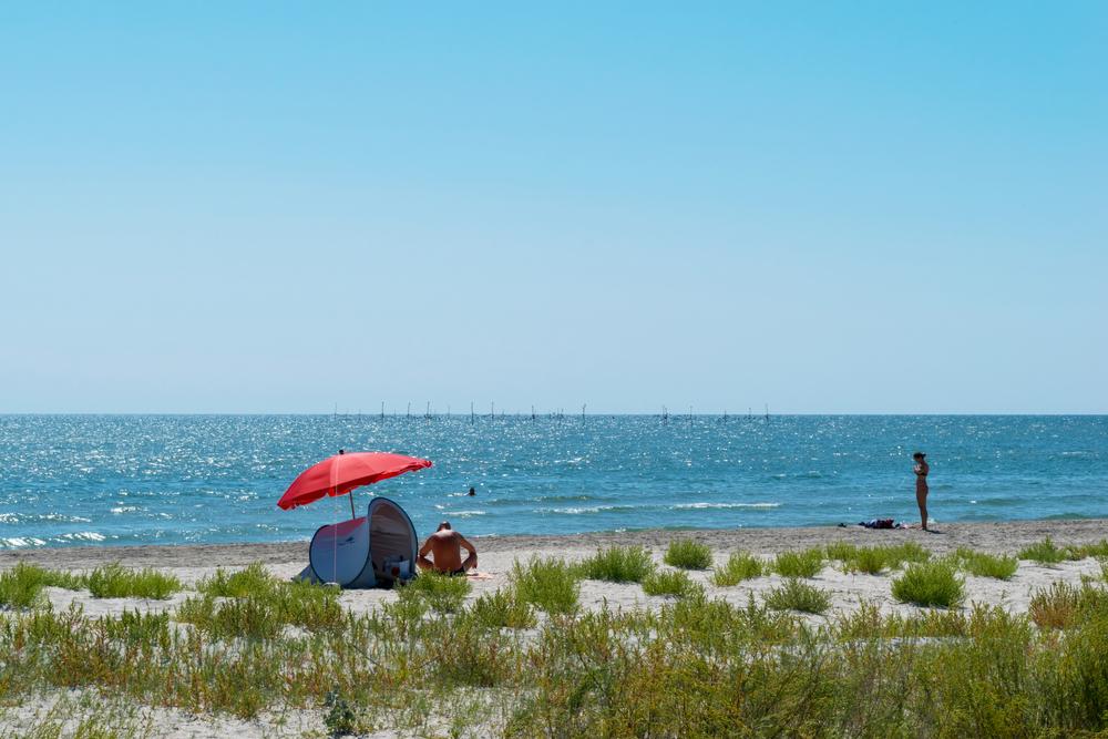 bărbat și femeie pe plajă la corbu sub umbrelă roșie