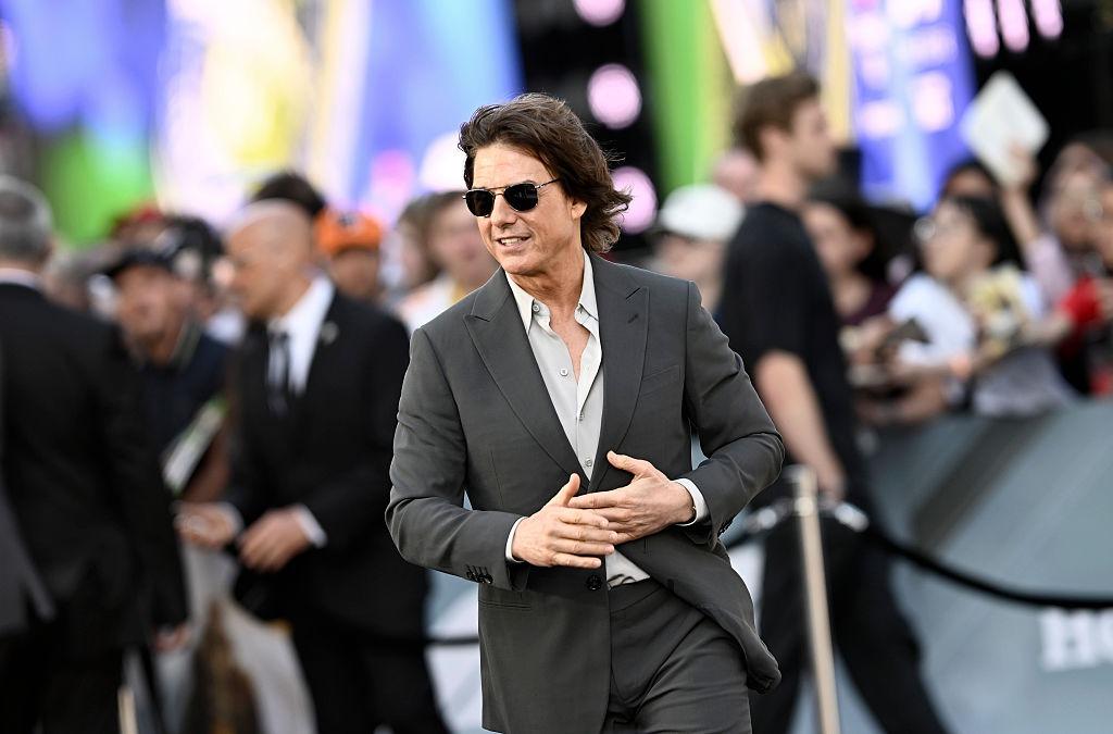 Tom Cruise îmbrăcat cu un costum gri, accesorizat cu ochelari de soare