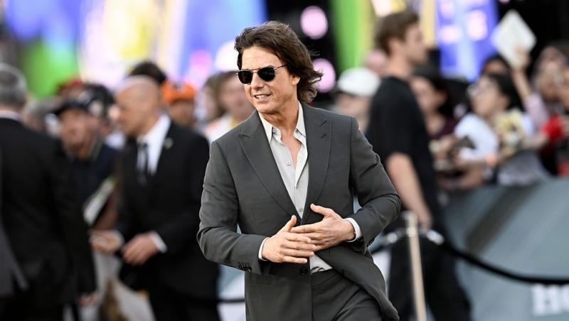 Tom Cruise îmbrăcat cu un costum gri, accesorizat cu ochelari de soare