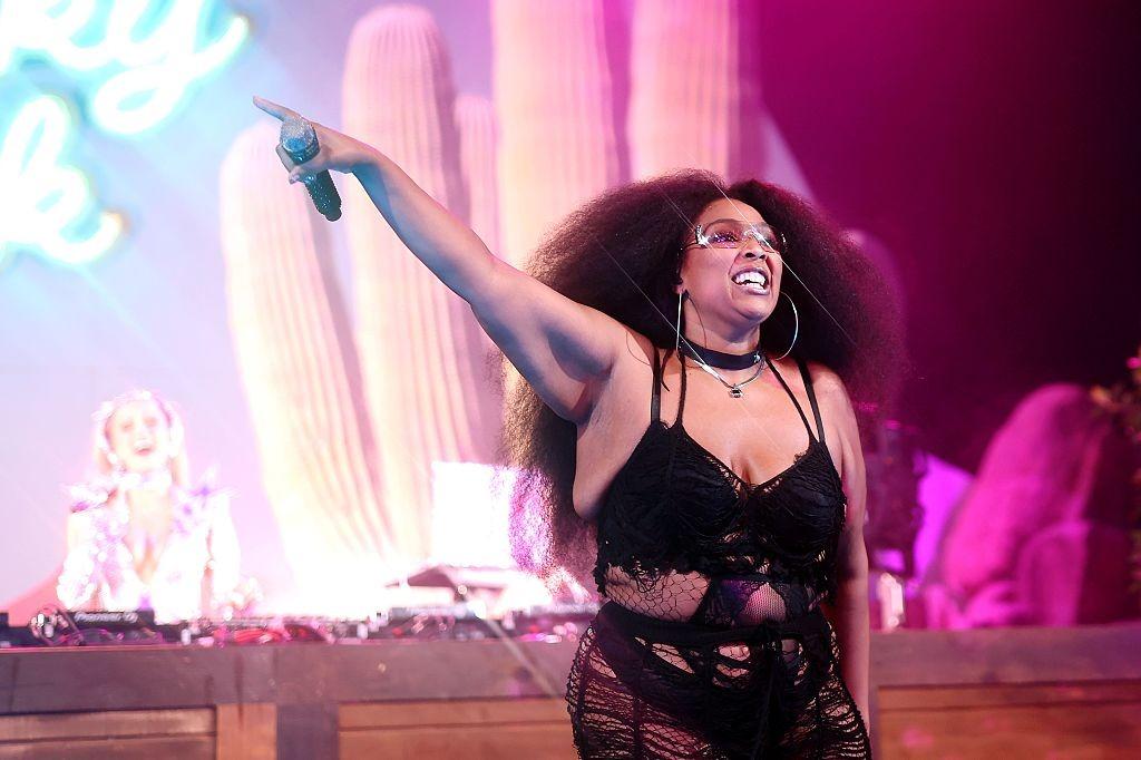 Lizzo îmbrăcată într-o ținută neagră, cântând și dansând pe scenă