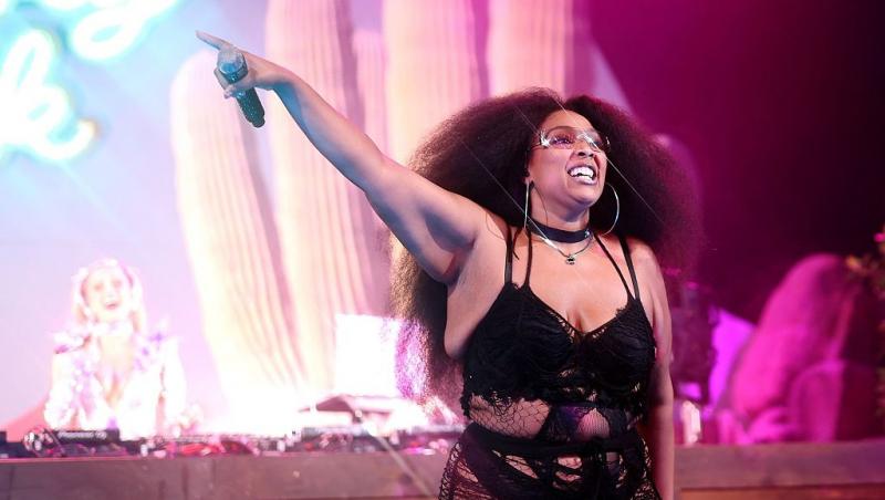Lizzo îmbrăcată într-o ținută neagră, cântând și dansând pe scenă