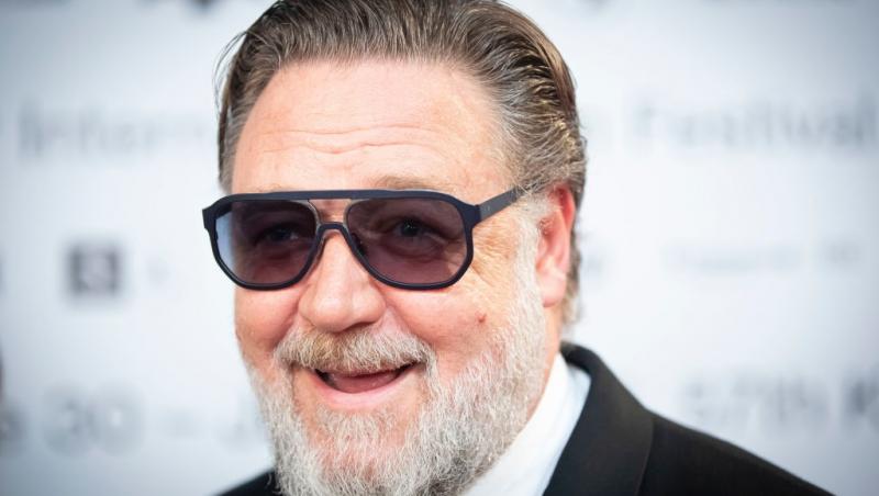 Russell Crowe îmbrăcat într-un costum negru, accesorizat cu ochelari de soare